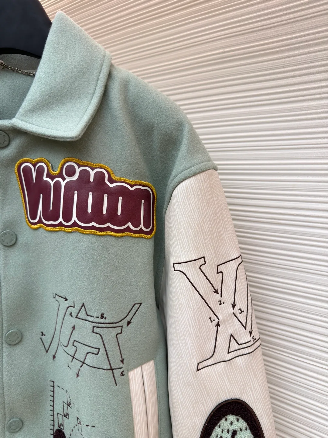 LOUIS VUITTON letter pattern patch printed color block baseball jersey ●Original version: 38999 purchase and development ●Item number: 1681672-D15 ●Fabric: sheep wool fabric ●Technology: printing production ●Color: green ●Version: fitted version ●Weight: about 1220 grams ●Size: 46-48-50-52 ●Description: This jacket is made of high-quality wool blended fabric, which is soft to the touch and has excellent warmth retention. The overall design adopts a lapel design, and the collar, cuffs and hem are all ribbed, with moderate elasticity, comfortable to wear and not easy to deform. The main part uses multi-color splicing technology. The gray and white splicing lines are smooth and natural, showing superb tailoring technology. The patterns on the chest and sleeves are embroidered and appliquéd, with distinct layers and a strong three-dimensional effect. Multi-colored silk threads are interwoven during the embroidery process to ensure that the pattern is clear and durable. The buttons of the jacket are made of metal, with a smooth surface and not easy to fade. The splicing of the shoulders and sleeves adopts seamless technology, with smooth and natural lines without excess threads. The overall workmanship is fine, and every stitch is even and neat, reflecting the high-quality production process. The overall wiring is straight and delicate, the fabric is comfortable and soft, and the color is consistent without color difference. It can be matched with the same style to create a fashionable look and control various occasions. Customized accessories, complete with three standards, same style for men and women!